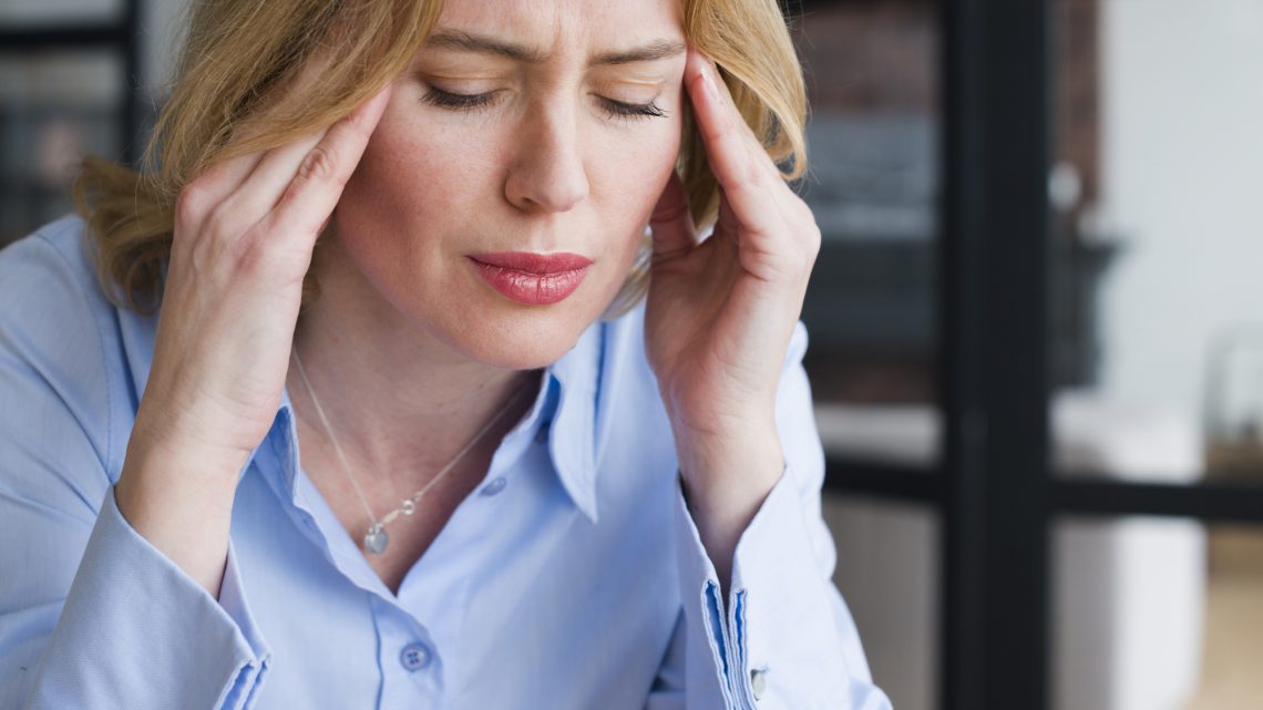 Headache, stress, woman holds her temples with her hands